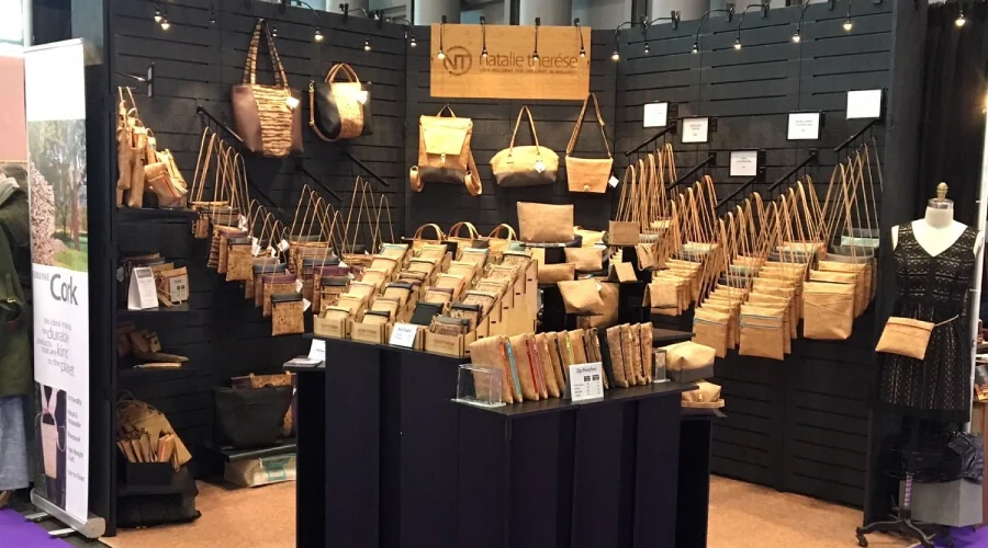 Trade show booth with handbags displayed on black slatwall panels